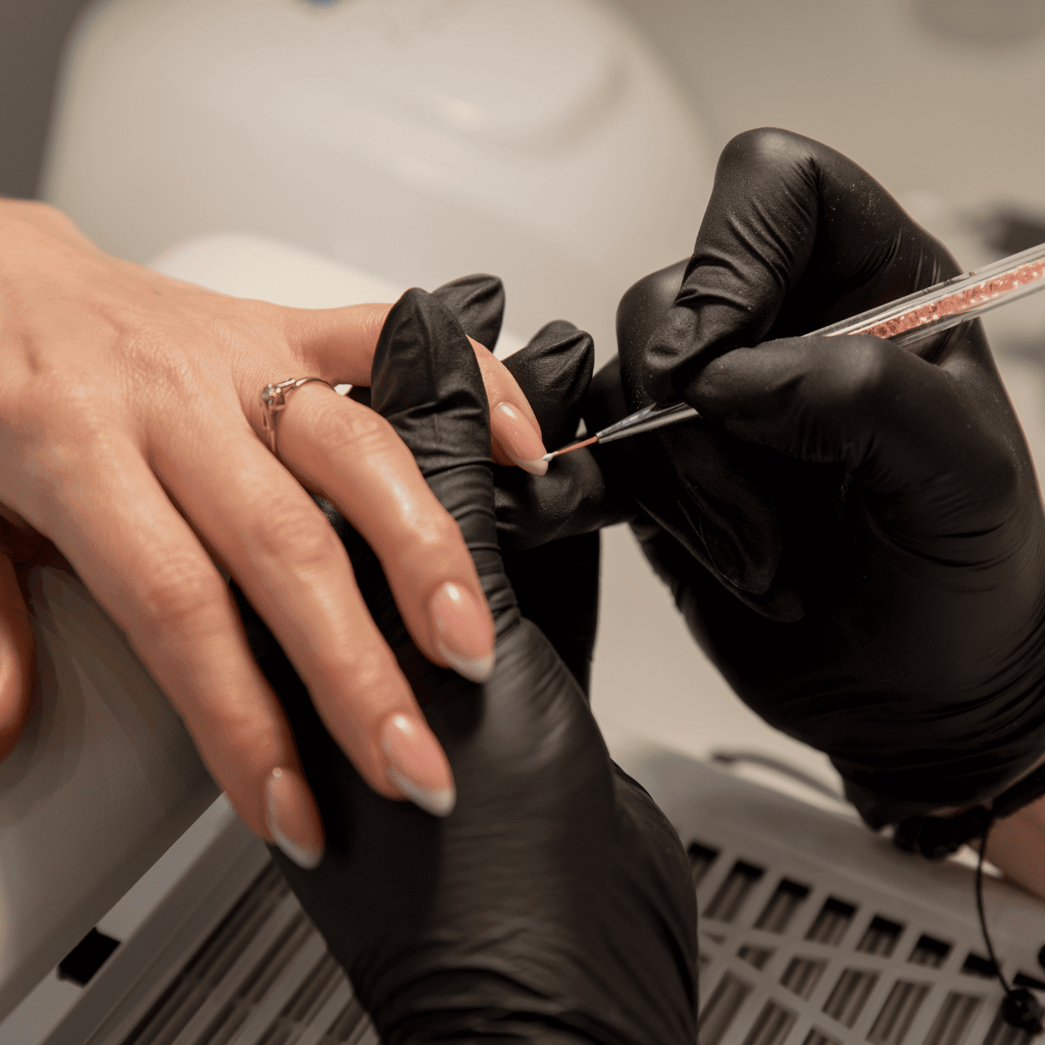 Close-up of a nail technician applying nail art to a woman's manicured nails.