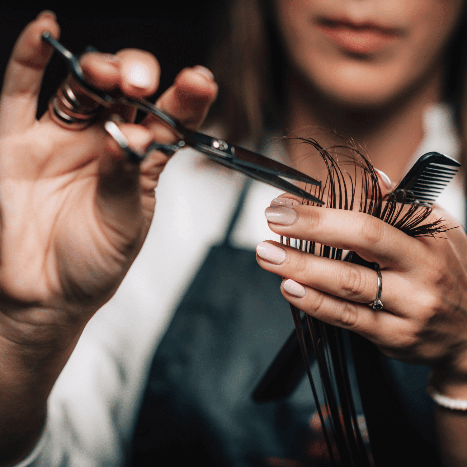 Close-up of a hairstylist cutting hair with scissors and a comb, showcasing precision and skill.